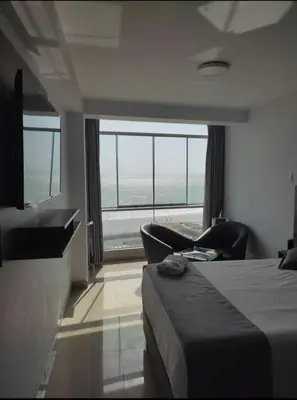 a bedroom with a bed and chairs and a large window at Hotel Terrazas Del Mar in Huacho