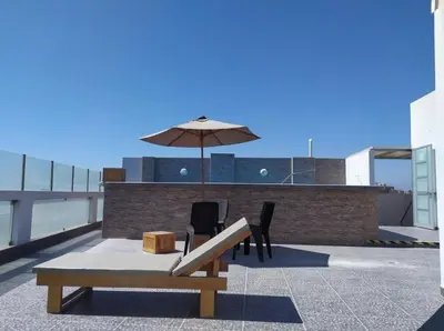 a bench and an umbrella on top of a building at Hotel Terrazas Del Mar in Huacho