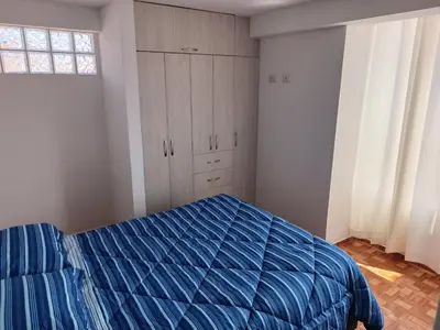 a bedroom with a blue bed and a window at Apart Cusco 