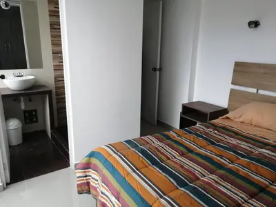 a bedroom with a bed and a bathroom with a sink at Apart Cusco 