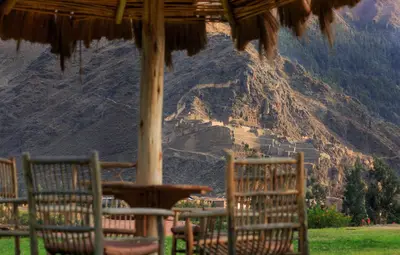 a table and chairs under an umbrella in front of a mountain at Tierra Viva Ollantaytambo in Ollantaytambo