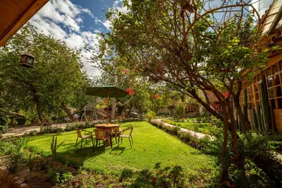 a garden with a table and chairs and an umbrella at IORANA HOTEL Urubamba in Urubamba