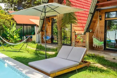 a hammock and an umbrella next to a house at Cabañas Alpinas en Oxapampa in Oxapampa