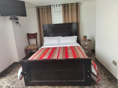a bedroom with a large bed and a television at Hostal Killaly Inn Cusco in Cusco