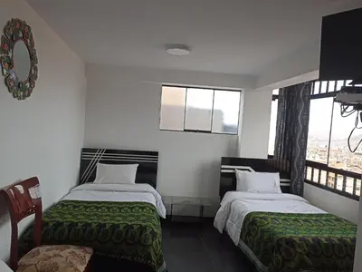 a bedroom with two beds and a window at Hostal Killaly Inn Cusco in Cusco