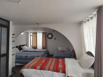 two beds in a room with an arched doorway at Hostal Killaly Inn Cusco in Cusco