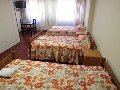 a room with three beds and a table at HOSPEDAJE LAS FLORES ICA in Ica