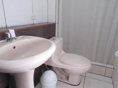 a bathroom with a white sink and a toilet at HOSPEDAJE LAS FLORES ICA in Ica