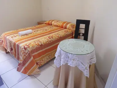 a bed with a table and a chair in a room at HOSPEDAJE LAS FLORES ICA in Ica