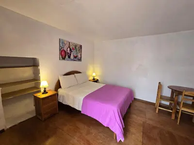 a bedroom with a bed with a purple blanket and a table at Barrio Inka B&B in Cusco
