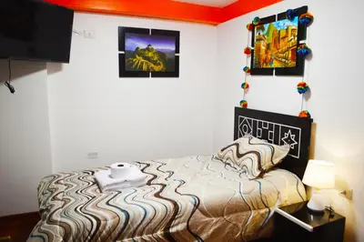 a bedroom with a bed and a tv on a wall at Qolmay Hostel Cusco in Cusco
