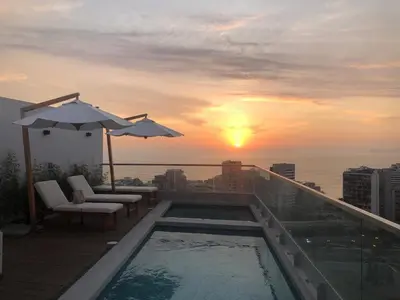 a balcony with a swimming pool and a sunset at Chic & Ocean View Apartment in Lima