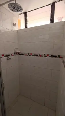 a bathroom with a shower with white tile at Los Apus Ollantaytambo in Ollantaytambo