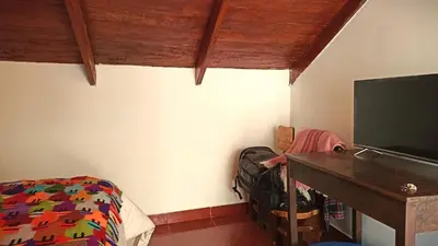 a bedroom with a bed and a desk and a television at Los Apus Ollantaytambo in Ollantaytambo