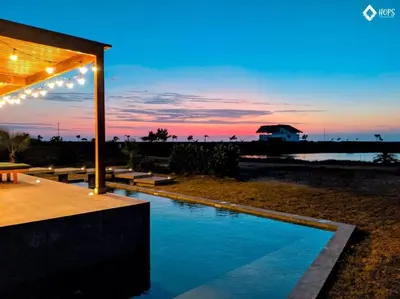 a swimming pool in front of a beach at sunset at HOP BUZIOS exclusiva oasis y playa en Chincha in Chincha Baja