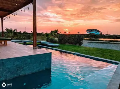 a swimming pool with a sunset in the background at HOP LAGO & MAR exclusiva en playa de chincha in Chincha Baja