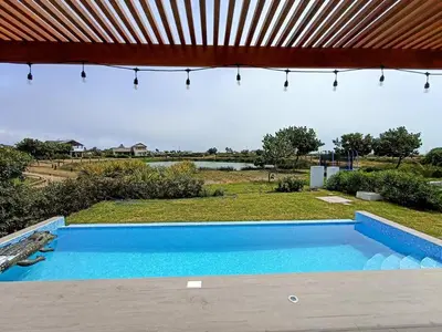 a blue swimming pool in a yard with a roof at HOP ODAIBA exclusiva laguna y playa en Chincha in Chincha Baja