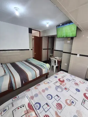 a hotel room with two beds and a flat screen tv at Hostal Jovita in Lima