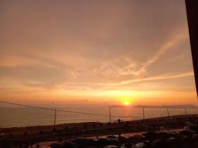a sunset over a beach with the sun setting over the ocean at Lugar encantador frente al mar con tina o jacuzzi in Lima