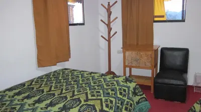 a bedroom with a bed and a chair and windows at Garden Inn 488 in Cusco