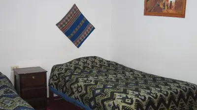 a bed in a room with a comforter on the wall at Garden Inn 488 in Cusco