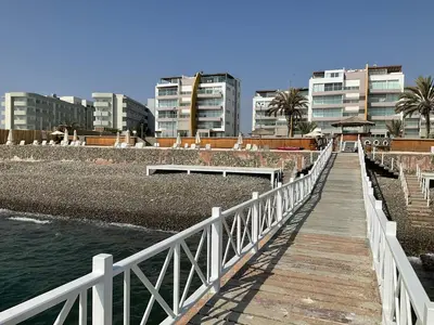 a wooden boardwalk leading to a beach with buildings at 1 Fila Vista Bahía Paracas - La Velas 501 T1 in Paracas