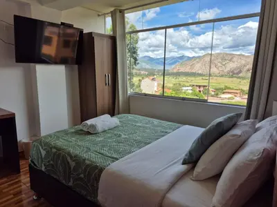 a bedroom with a bed with a large window at Casa Yanahuara Valle Sagrado - Urubamba in Urubamba