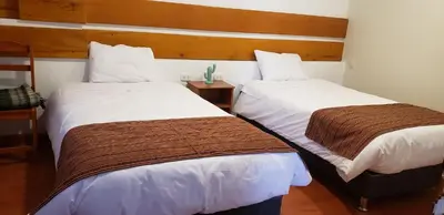 two beds in a hotel room with white and brown sheets at Tilcafé B&B Mollepata in Mollepata