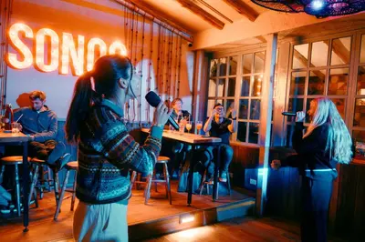 a woman standing in a restaurant holding a microphone at Viajero Cusco Hostel in Cusco