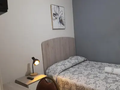 a bedroom with a bed and a table with a lamp at Casa Las Flores Ica in Ica