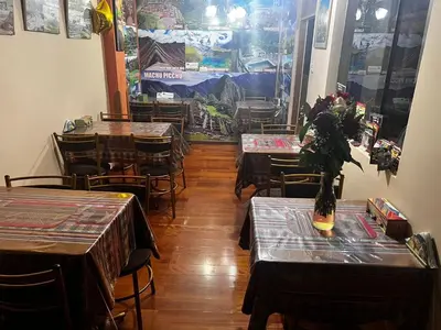 a restaurant with tables and chairs and a vase of flowers at Hotel Colquewasi in Cusco