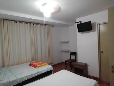 a hotel room with two beds and a tv at Icthus Paracas in Paracas