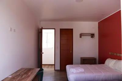 a bedroom with a bed and a table and a door at La Estancia Hotel Ica in Ica