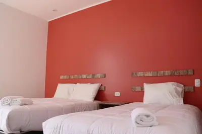 two beds in a room with red walls at La Estancia Hotel Ica in Ica