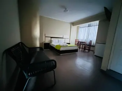 a bedroom with a bed and chairs in a room at Hotel La Suite de Angelique Huacho in Huacho