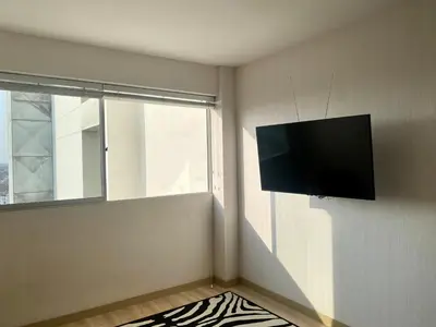 a living room with a flat screen tv on the wall at Céntrico mini departamento, moderno y acogedor in Lima