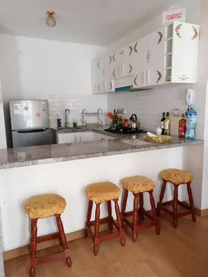 a kitchen with three bar stools and a counter at VERSALLES APARTMENT in Lima