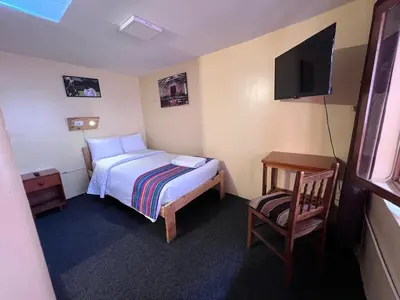 a bedroom with a bed and a tv and a chair at Eco Inn in Cusco