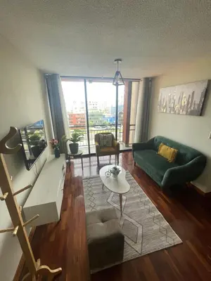 a living room with a green couch and a table at Departamento completo en Miraflores Surquillo in Lima