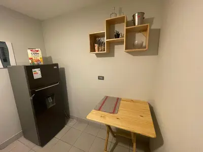 a small kitchen with a table and a refrigerator at Departamento completo en Miraflores Surquillo in Lima