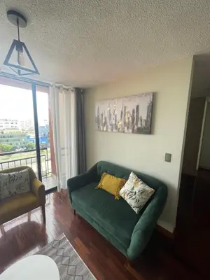 a living room with a green couch and a window at Departamento completo en Miraflores Surquillo in Lima
