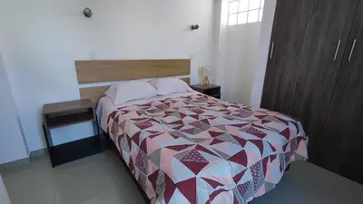 a bedroom with a bed and a table with a bedspread at III Zaguan Aparta Hotel Cusco in Cusco