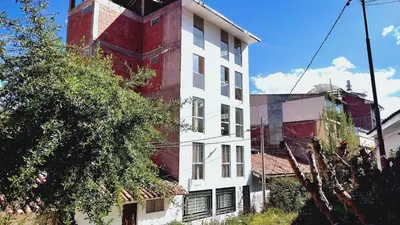a white and red building next to a tree at III Zaguan Aparta Hotel Cusco in Cusco