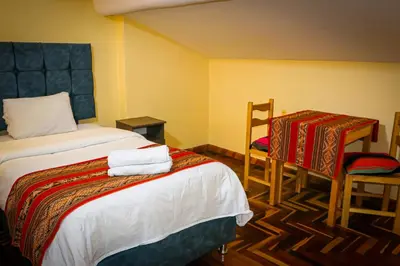 a hotel room with a bed and a table and chairs at Cusco Hawka Pacha hostal in Cusco