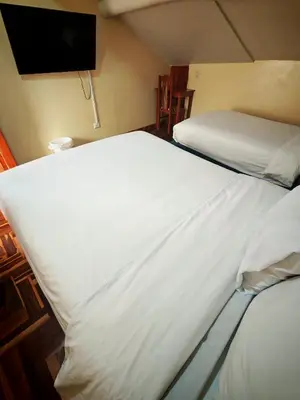 a bedroom with two beds and a flat screen tv at Cusco Hawka Pacha hostal in Cusco