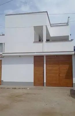 a white building with two garage doors in a driveway at Departamentos Cerro Azul P2 in Cerro Azul