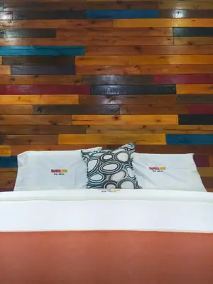 a bed with two pillows on it with a wooden wall at Sumaq Wari Hotel in Ayacucho