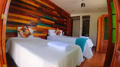 a bedroom with two beds and a wooden wall at Sumaq Wari Hotel in Ayacucho