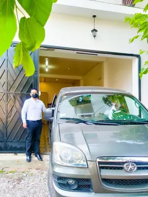 a man standing next to a car in front of a garage at Sumaq Wari Hotel in Ayacucho
