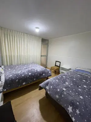 a bedroom with two beds and a chair at Casa 1er piso D&C in Huancayo